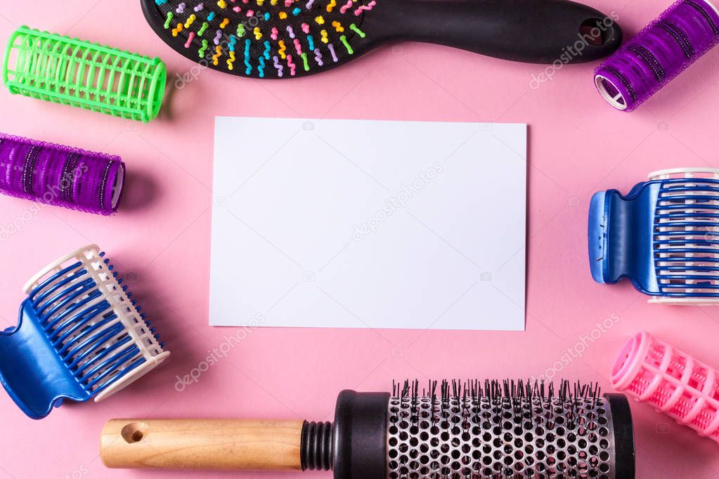 Hair curlers, combs and blank sheet of paper on a pink background. Hairdressing Supplies. Top view