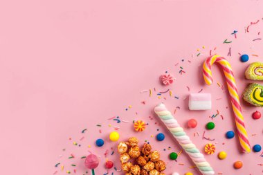 Renkli, şeker, tatlı şeker, reçel, hatmi, karamelli patlamış mısır, chupa chups pembe bir arka plan üzerinde. Bir sehpa dolusu şeker. Uzay kopyalayın. Üstten görünüm, tatlılar kavramı