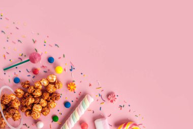 Renkli, şeker, tatlı şeker, reçel, hatmi, karamelli patlamış mısır, chupa chups pembe bir arka plan üzerinde. Bir sehpa dolusu şeker. Uzay kopyalayın. Üstten görünüm