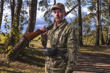 Bir avcı av silah ve bir arka plan ağaç ormandaki şeklinde portresi. Avcılık kavramı