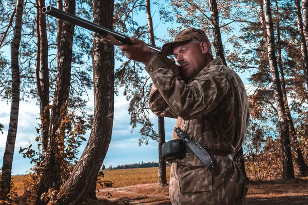 A hunter with a hunting gun and hunting form to hunt in an autumn forest.