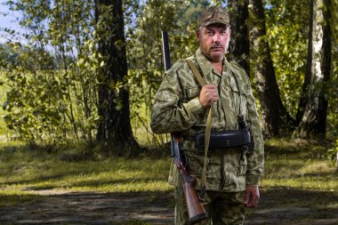 Bir avcı av silah ve bir sonbahar ormandaki ağaçlar bir arka plan şeklinde portresi. Avcılık oncept.