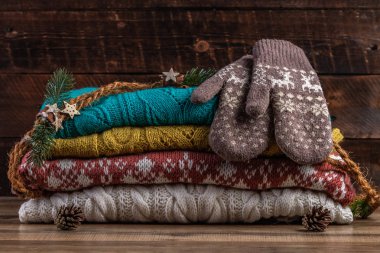 Örme, kış kazak ve ahşap arka plan üzerinde sıcak mittens. Kış ve sonbahar kıyafetleri.