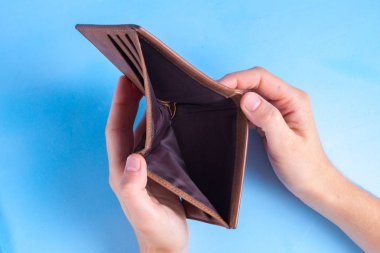 Bir adam bir boş cüzdan mavi bir arka plan üzerinde tutuyor. Finansal kriz. Para ile ilgili sorunlar. Para eksikliği