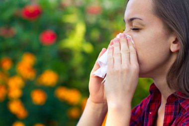 Çiçekli alerjisi. Polen sneezing ve akıntısı burun. Alerjik reaksiyonlar. Bir kadın parkta bir mendil tutan ve çiçek ve polen bloom hapşırma