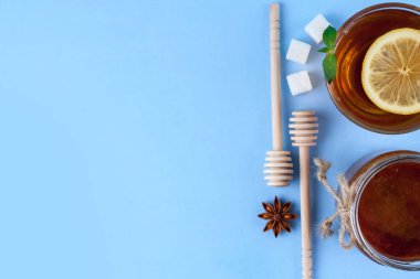 Çay içme. Bir fincan çay taze nane ve limon sulu, bal kavanozu ve bal kaşık, rafinated şeker, bir dilim anisetree mavi bir arka plan üzerinde. Üstten görünüm. Kopya alanı 