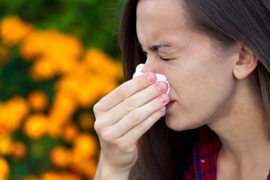 Çiçekli alerjisi. Polen sneezing ve akıntısı burun. Alerjik reaksiyonlar. Bir kadın parkta bir mendil tutan ve çiçek ve polen bloom hapşırma