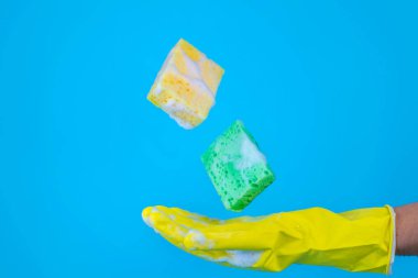 Mavi bir arka plan üzerinde bulaşık için uçan sünger. Temizlik kavramı