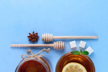 Çay içme. Bir fincan çay taze nane ve limon sulu, bal kavanozu ve bal kaşık, rafinated şeker, bir dilim anisetree mavi bir arka plan üzerinde. Üstten görünüm. Kopya alanı 