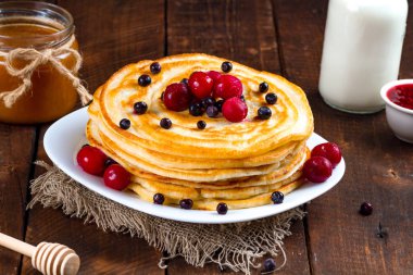 Yaban mersini ve kiraz, frambuaz reçeli, süt ve bal ahşap arka plan üzerinde taze çilek ile krep. Lezzetli, sağlıklı kahvaltı