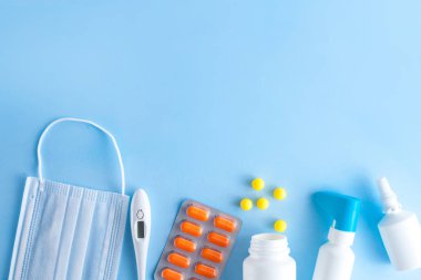 Soğuk algınlığı ve grip tedavisinde. Çeşitli ilaçlar, bir termometre, spreyler tıkalı burun ve boğaz üzerinde mavi bir arka plan baş belası. Uzay kopyalayın. Tıp düz yatıyordu. 