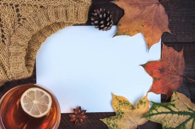 Örme kazak, sonbahar, akçaağaç yaprakları ve ahşap arka plan üzerinde Limonlu sıcak çay. Kış ve sonbahar giysileri. Uzay kopyalayın. Üstten görünüm. Sıcak, rahat kıyafetler