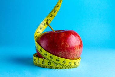 Diyet kavramı. Ağırlık comcept kaybetme. Sarı ölçüm bandı ve mavi bir arka plan üzerinde bir elma.