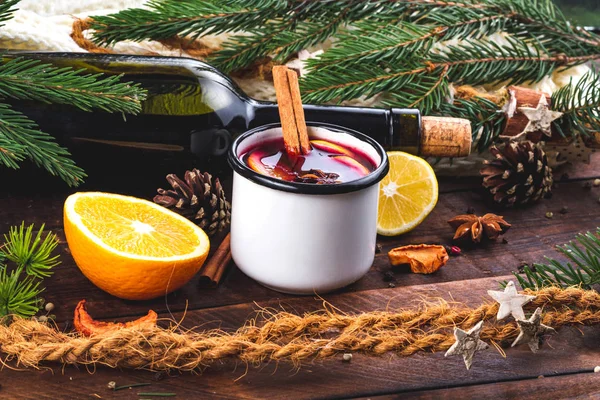 stock image Mulled wine, a bottle of red wine, spruce branches, cinnamon, anise tree, orange and lemon on a wooden background. A cozy, winter evening. Winter drinks. Christmas Eve