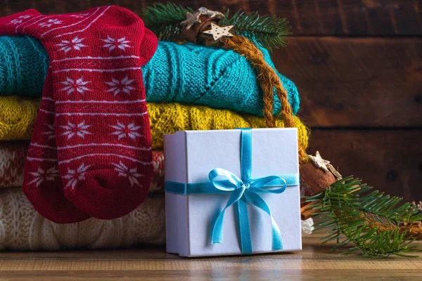 Winter, warm, knitted pullovers, socks, Christmas gift and a mug of hot cocoa on a wooden background. Winter clothes. Ugly Christmas Sweater