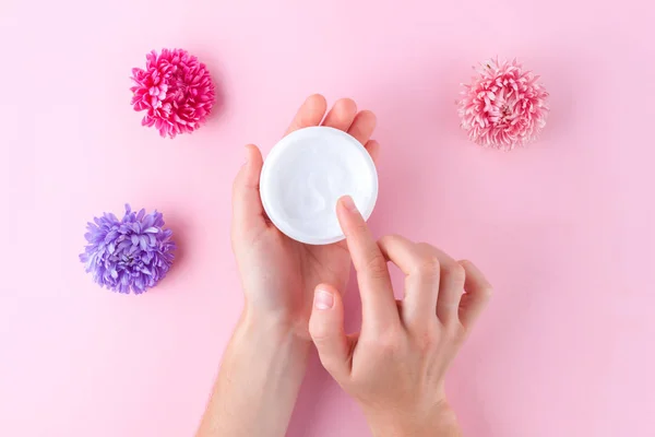 Hand cream and flowers on a pink background. Skin and hand care. Moisturizing and eliminating the dryness of the hands skin