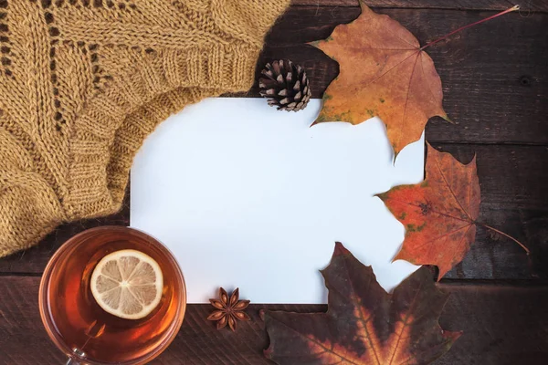 Örme kazak, sonbahar, akçaağaç yaprakları ve ahşap arka plan üzerinde Limonlu sıcak çay. Kış ve sonbahar giysileri. Uzay kopyalayın. Üstten görünüm. Sıcak, rahat kıyafetler