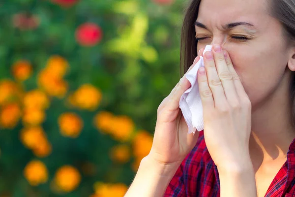 開花するアレルギーです 花粉からくしゃみや鼻水の鼻 アレルギー反応 公園で女性がハンカチを保持し 花や花粉の開花からくしゃみ — ストック写真