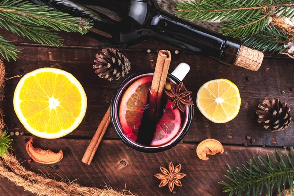 Mulled wine, a bottle of red wine, spruce branches, cinnamon, anise tree, orange and lemon on a wooden background. A cozy, winter evening. Winter drinks. Flat lay