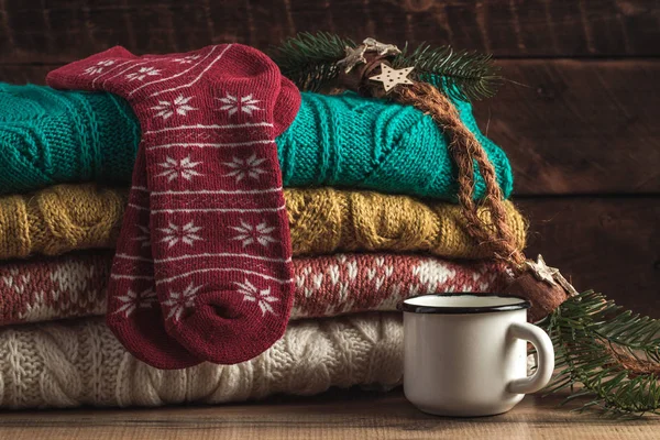 Winter, warm, knitted pullovers, Christmas socks and a mug of hot cocoa on a wooden background. Winter clothes. Ugly Christmas Sweater