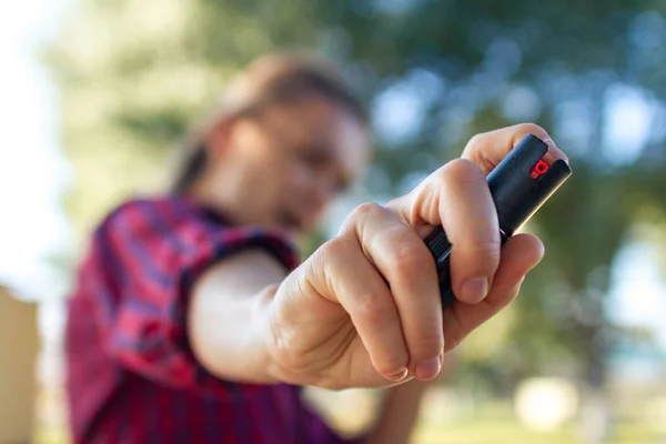 Self-defense. A young woman protects herself in the park from criminals, thieves and hooligans with the help of pepper spray. Self defense woman