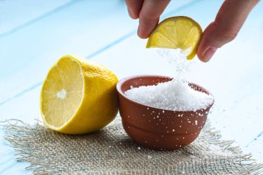 Kahverengi, küçük bir tabak, bir dilim limon elinde ve ahşap arka plan üzerinde sulu limon limon asidi. Sitrik asit. 