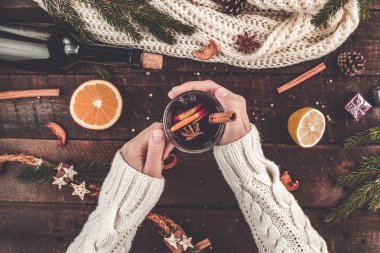 Sıcak genç bir kadın, kazak örme, beyaz bir Noel, sıcak mulled şarap bir cam baharat ve narenciye ile tutuyor. Rahat, kış bir akşam. Kış içer. Düz yatıyordu, en iyi görünümü 