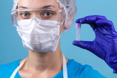 Bir asistan gözlük, medikal maske, medikal ürünler, laboratuvar üniforma tüp bebek onun elinde tutar. Laboratuvar, tıbbi testler ve araştırma.