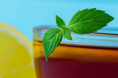 Çay içme. Bir fincan çay taze nane ve mavi bir arka plan üzerinde sulu limon bir dilim ile.
