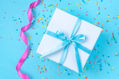 Hediye, küçük kutu mavi bir arka plan üzerinde mavi bir saten kurdele ile bağlı. Hediyelik konsepti. Sürprizler ve sevdiklerinize, tatil, tebrikler için hediye hediyeler vermek