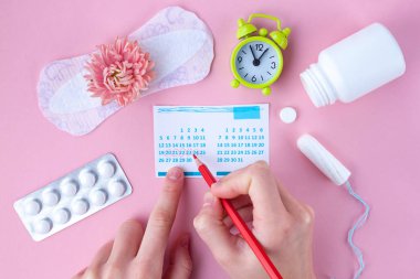Tampon, feminen, sıhhi pads için kritik gün, kadınsı takvim, çalar saat, menstruasyon sırasında ağrı kesici ve pembe bir arka plan üzerinde pembe bir çiçek. Menstruasyon sırasında hijyen bakım. Düzenli adet döngüsü. Aylık koruma
