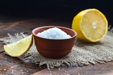 Kahverengi, küçük bir tabak, bir dilim limon ve ahşap arka plan üzerinde sulu limon limon asidi. Sitrik asit