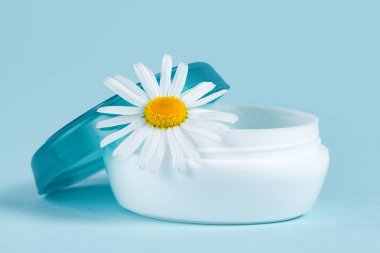 Nemlendirici El Kremi Kuru cilt ve papatya çiçek mavi bir arka plan üzerinde. Cilt Bakımı