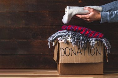 Donation concept. Donation box with donation clothes on a wooden background. Charity. Helping poor and needy people clipart