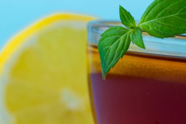 Çay içme. Bir fincan çay taze nane ve mavi bir arka plan üzerinde sulu limon bir dilim ile.