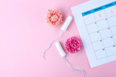 Düzenli adet döngüsü. Tampon, kadın takvim, pembe bir arka plan üzerinde çiçekler. Hijyen bakımı sırasında kritik gün. Kadın ve jinekolojik sağlık. Hijyen