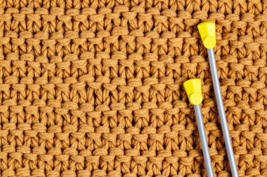 Sarı bir örme iplik ve örme iğneler doku. Örme ve kış giysileri. Kopya alanı 