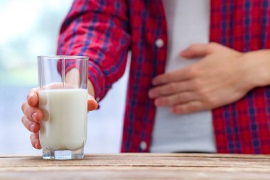Bir kadın kendini kötü hissediyor, bir mide laktoz intoleransı nedeniyle şişkinlik vardır. Süt şekeri hastası kişi. Sağlık kavramı. Laktoz intoleransı ve süt ürünleri