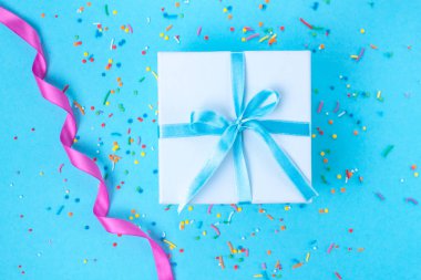 Hediye, küçük kutu mavi bir arka plan üzerinde mavi bir saten kurdele ile bağlı. Hediyelik konsepti. Sürprizler ve sevdiklerinize, tatil, tebrikler için hediye hediyeler vermek