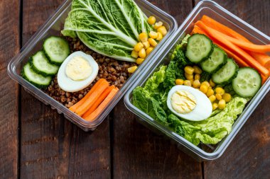 Plastik bir kap içinde sağlıklı yemek. Ofiste, işyerinde yemek saati. Öğle yemeği kutusu ahşap arka plan üzerinde. Doğru ve sağlıklı gıda kavramı. Diyet 