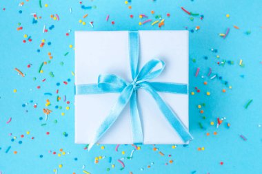 Hediye, küçük kutu mavi bir arka plan üzerinde mavi bir saten kurdele ile bağlı. Hediyelik konsepti.