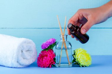 Spa. Hava difüzörü, uçucu, aroma petrol şişe el, havlu ve mavi bir arka plan üzerinde çiçekler. Aromaterapi, gevşeme. Spa uygulamaları