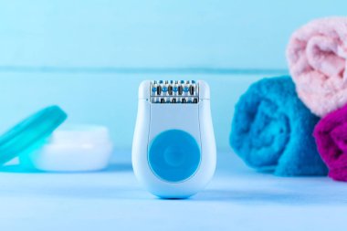 Mavi bir arka plan üzerinde epilatör, krem, havlu. Depilatory. İstenmeyen saç kaldırılması. 