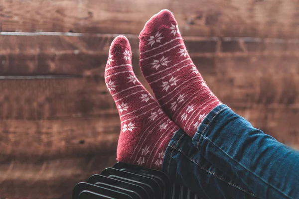 Women\'s feet in Christmas, warm, winter socks on the heater. Keep warm in the winter, cold evenings. Heating seaso
