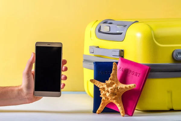 Online booking. Booking tickets and hotels on the Internet. A bright, yellow travel suitcase, passports and starfish on a yellow background. Travel concept. Leisure, vacation