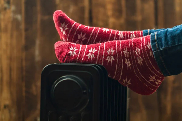 Women's feet in Christmas, warm, winter socks on the heater. Keep warm in the winter, cold evenings. Heating seaso