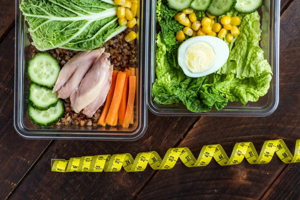 Healthy, dietary meal in a plastic container and a measuring tape. Lunch box. Nutrition and healthy food concept. Diet and weight loss concept. Eat right and monitor your health.