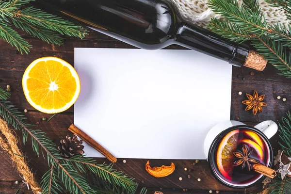 Mug of hot mulled wine with spices, citrus fruits, cinnamon and anise stars on a wooden background. Copy space. Top view. Flat lay. Mulled wine background. Winter drinks. Christmas, cozy evening