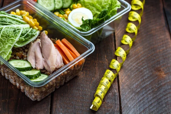 Healthy, dietary meal in a plastic container and a measuring tape. Lunch box. Nutrition and healthy food concept. Diet and weight loss concept. Eat right and monitor your health.