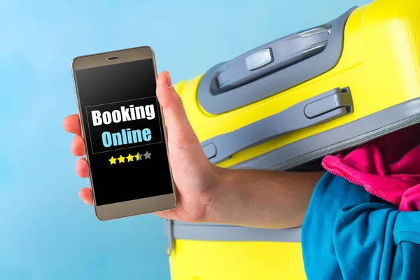 Online booking. Booking tickets and hotels on the Internet. Travel suitcase full of clothes on a blue background. Travel concept. Leisure, vacation